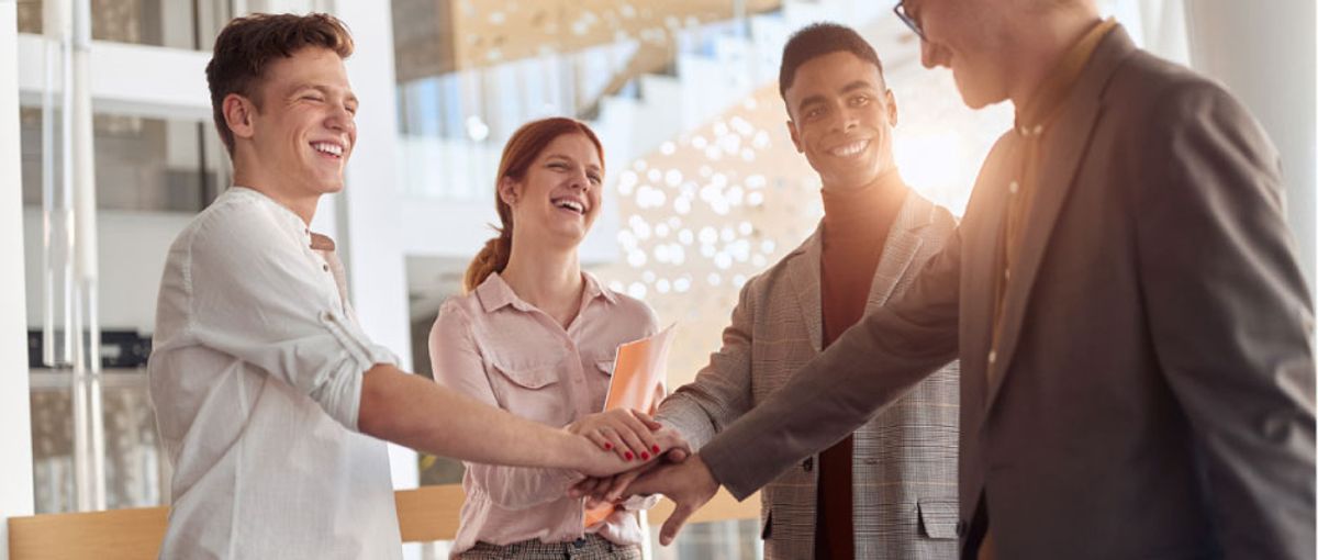 Group of professionals standing in a circle and putting their hands together as a team activity.