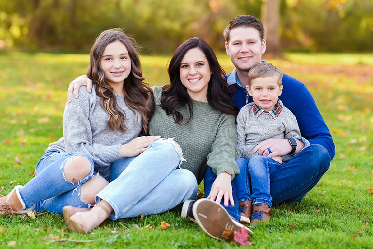 Seated on lawn in civilian clothing with wife and two children