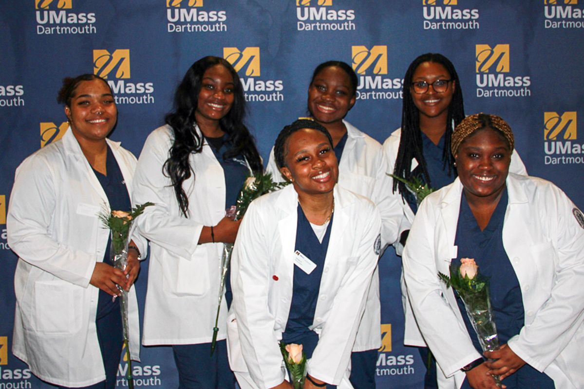 Group of nursing students in white lab coats with roses