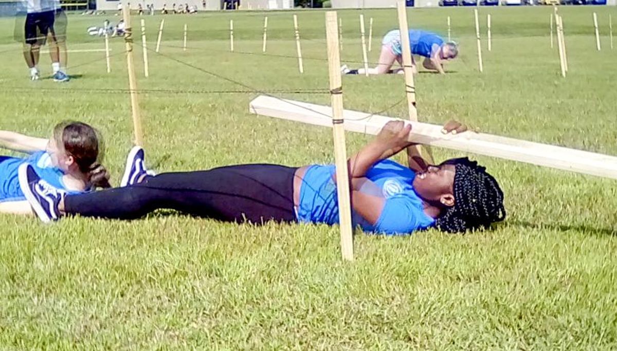 Student holding a wooden plank during the obstacle course