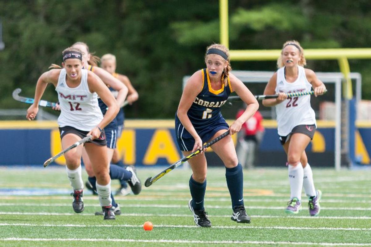 Mary Brown running with her field hockey stick toward the ball on the field