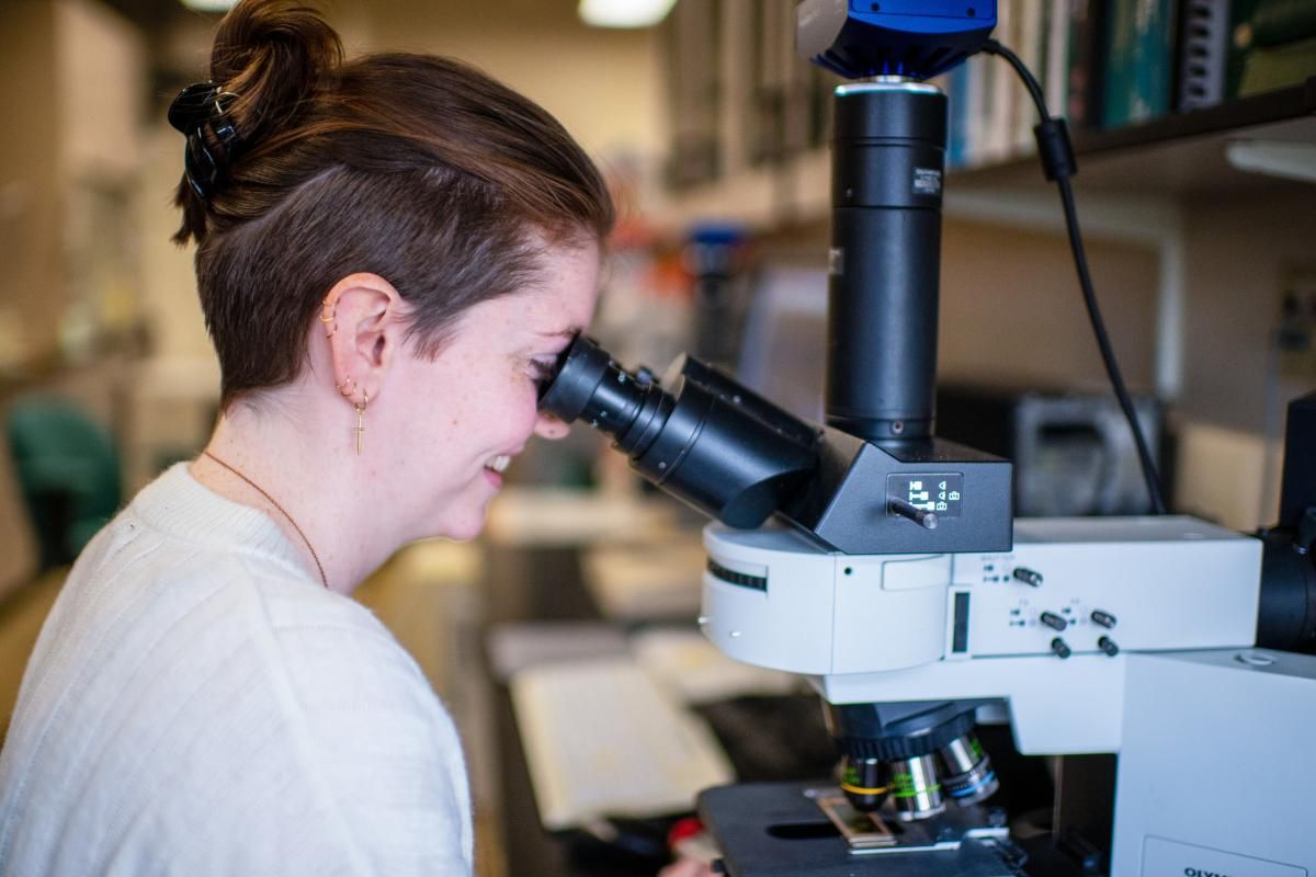 SMAST student Emma Gallagher looking into a microscope in Dr. Jefferson Turner's lab
