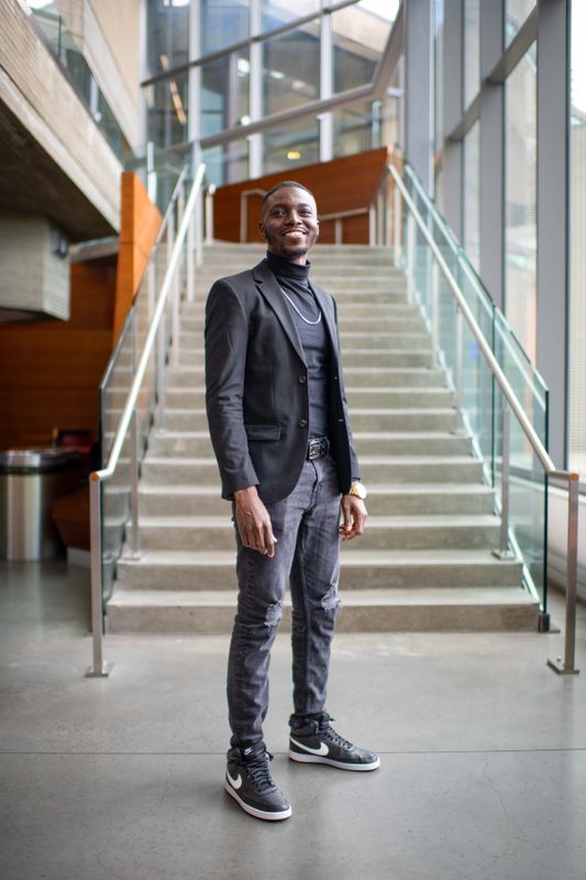 Gaspard Baye stands in the library in front of the staircase