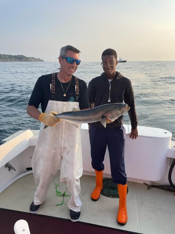 SMAST intern Kenry with first mate Eric holding a blue fish