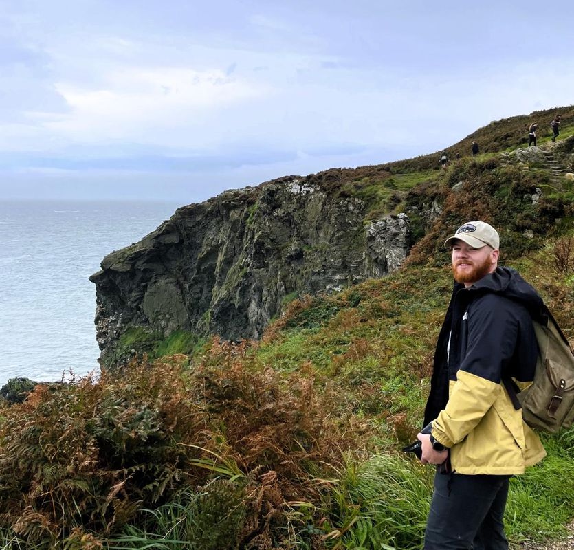 Joshua Cameron standing in front of cliffs in Ireland