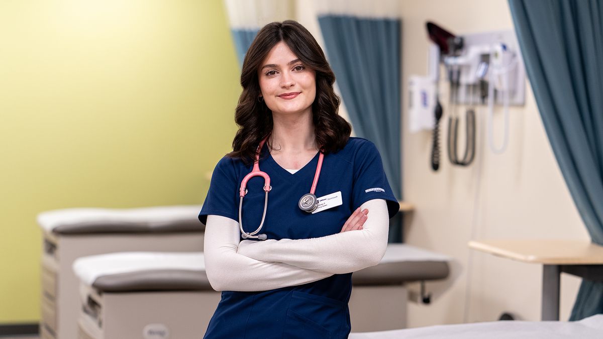 Portrait of Aubrey Fazzone '26, standing in the nursing simulation lab wearing scrubs