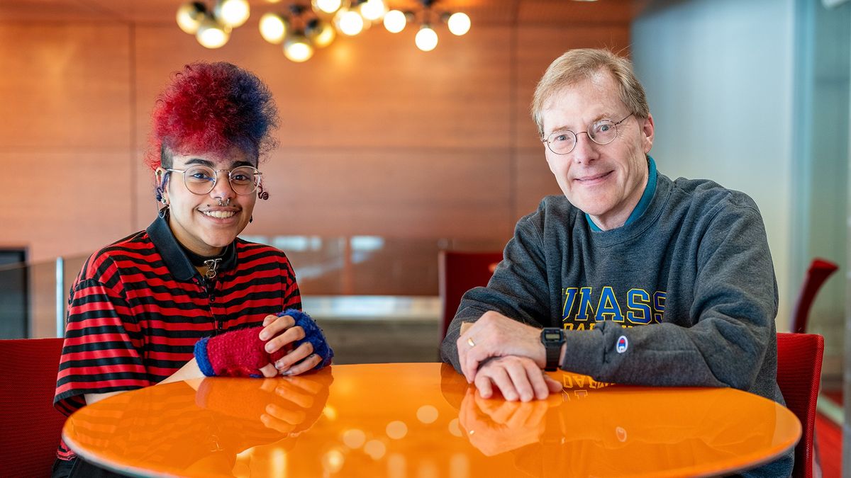 Kol Tavares '27 and Professor Robert Darst sitting beside each other at a table and smiling at the camera.