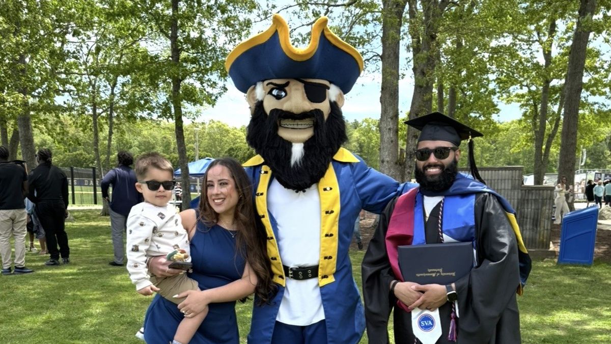 John Augusta MS '26 and his family posing with Arnie at Commencement