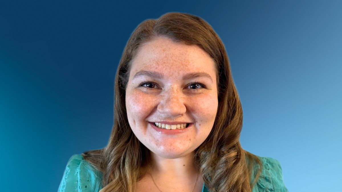 Kayla Alvares BSN MSN PhD smiling in front of a blue background