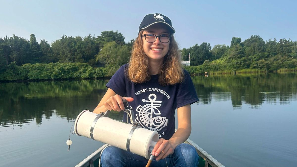 Mia Oliveira '26 sitting on a boat smiling while holding research equipment