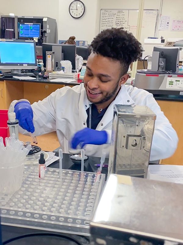 Wearing lab coat, working in MLS lab