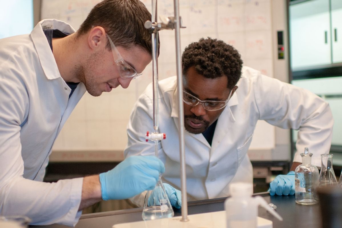 Two male civil engineering students with liquid in beaker