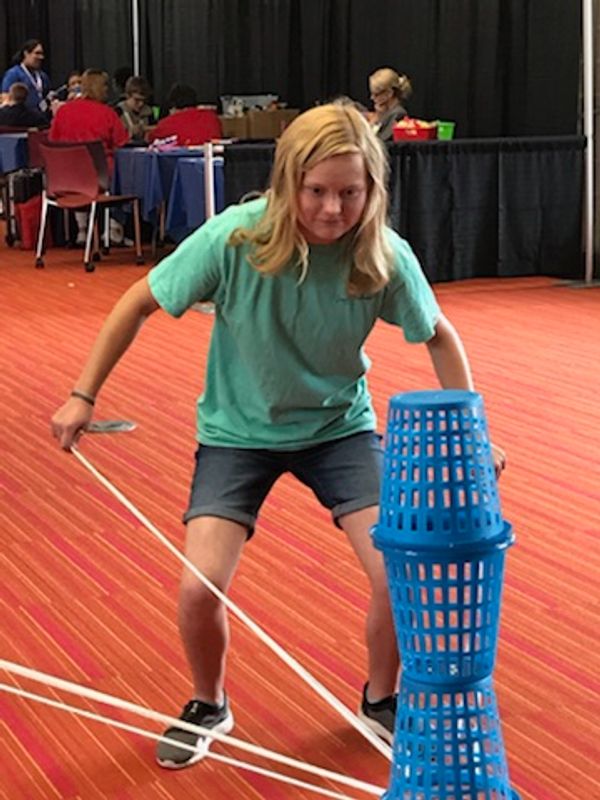 Female student balancing baskets during String Lift at the STEM Expo