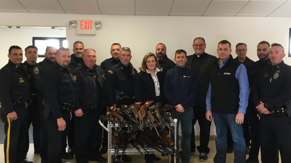 Police officers and university officials around donated guns at gun giveback event