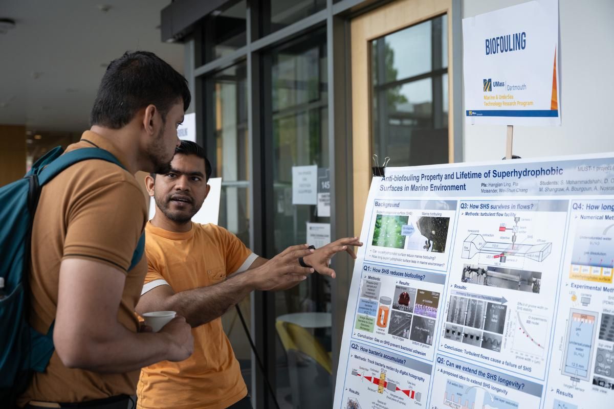Students standing by posterboards showcasing research