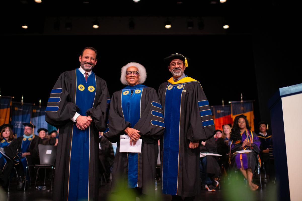 Dean, Guest, and provost posing for photo on stage