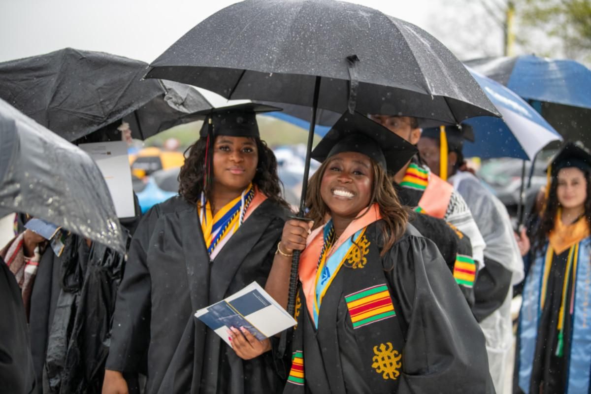 Two students in graduation regalia smiling