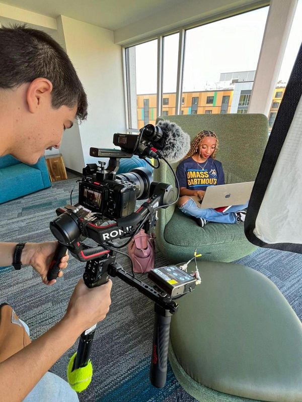 Student posing with book for video cameras