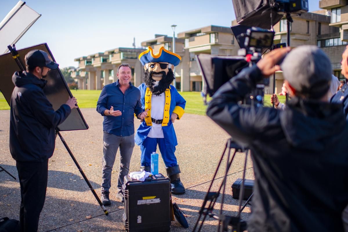Tv show host poses for camera with Arnie mascot