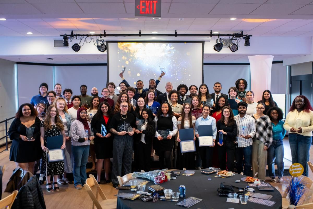 large group of students with awards posing on stage