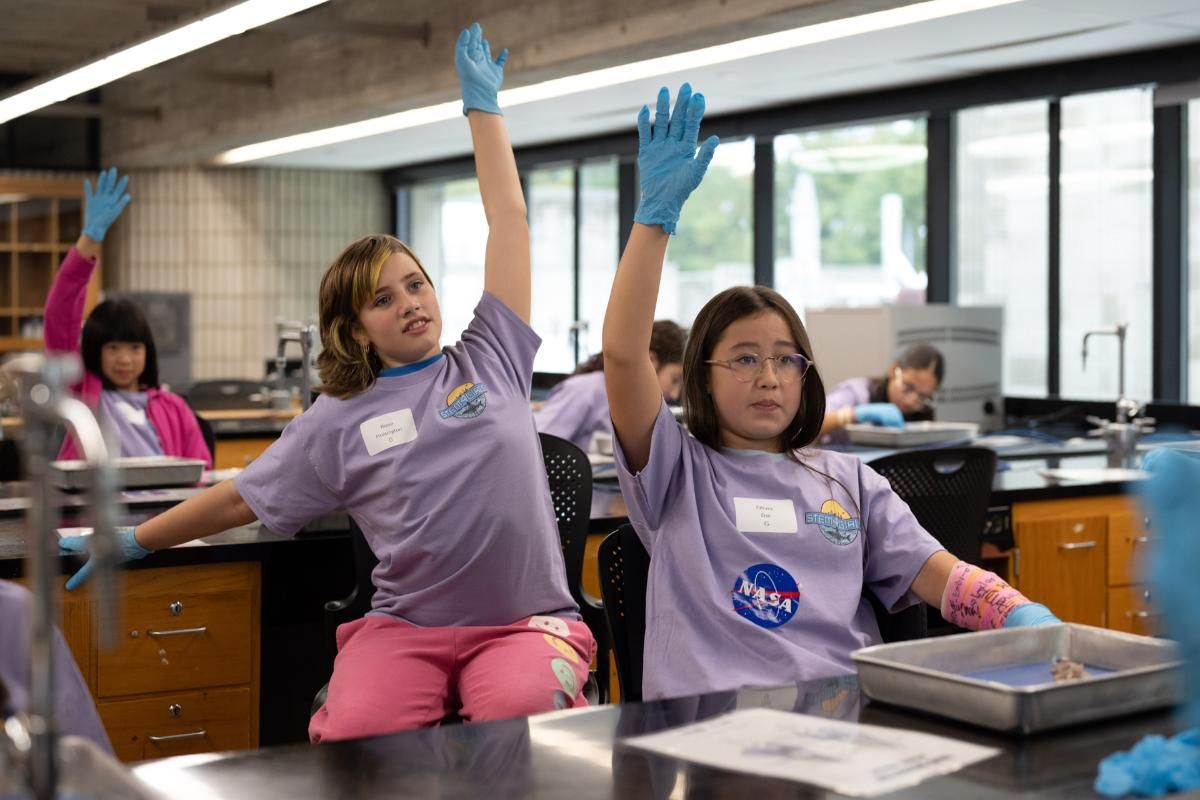 Students in the STEM4Girls program raising their hands to answer a question