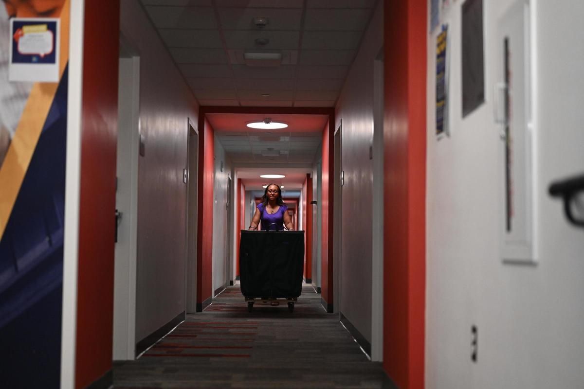 student pushing moving bin down hallway
