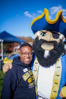 A smiling UMassD staff member poses with Arnie during the Blue & Gold Family Festival.