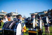 A student drummer with blue face paint smiles while holding drumsticks in front of a bass drum during the Blue & Gold Family Festival