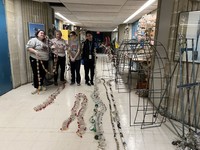 Students from alternative spring break string bottles for the sculpture Monster