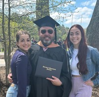Giesta poses with his wife and daughter at commencement.