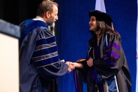 Aguilar Delgado pictured at commencement shaking the hand of UMass Law Dean Sam Panarella.