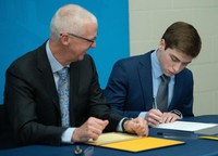 Zachary Gay signing scholarship certificate with Chancellor Fuller