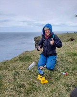 Biology major Eva Lavoie working on a cliff on the coast of Iceland.