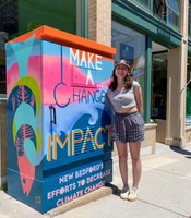 Graphic design major Ruby Louro, 2022 winner, with her electrical box on Union St in New Bedford.
