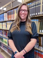 Student standing in front of library book stack