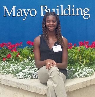 Biology student sitting in front of Mayo Clinic sign