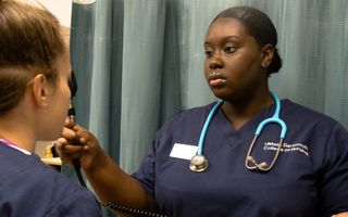 African-American student working with another student in the nursing lab