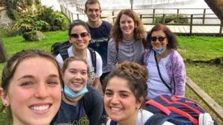 Students and faculty standing in front of a waterfall