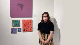 Tia Arce with paintings in Campus Gallery
