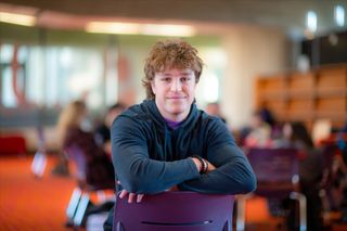 Student Christian Fall seated in the library living room