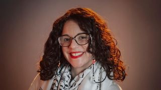 A headshot of Jessica Pabón '01 smiling in front of a brown background.