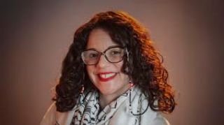 A headshot of Jessica Pabón '01 smiling in front of a brown background.