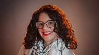 A headshot of Jessica Pabón '01 smiling in front of a brown background.