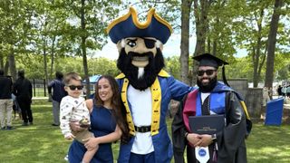 John Augusta MS '26 and his family posing with Arnie at Commencement