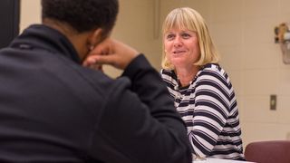 Seated faculty member talking to student