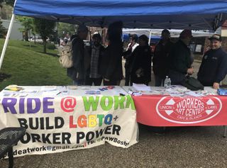 Individuals standing at Workers Art Center Pride center booth tables