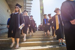 Students in regalia walking down the stairs