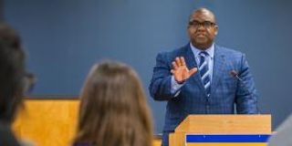Judge stands at lectern with students in the foreground
