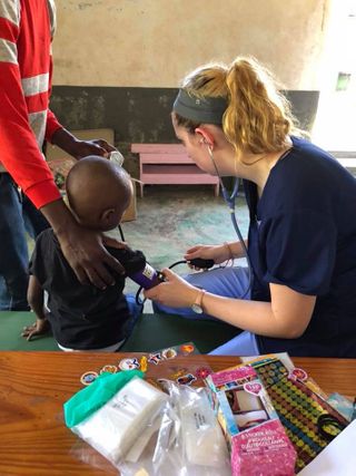 Nursing student taking blood pressure of young child in Haiti