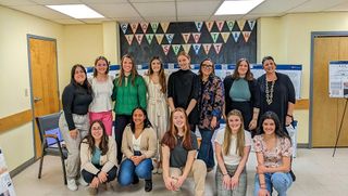IAD 302: Institutional Design students pose at a presentation of their designs for renovations to CO-OP